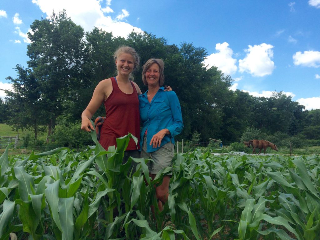 two women smiling in a field of corn